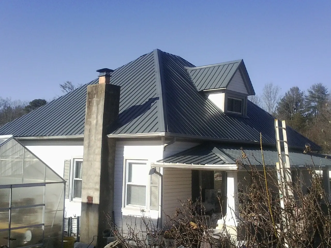 Dark blue standing seam metal roof on a white farmhouse with dormer — Slate & Tile Roof Repair by Roofing Brothers in Martinez