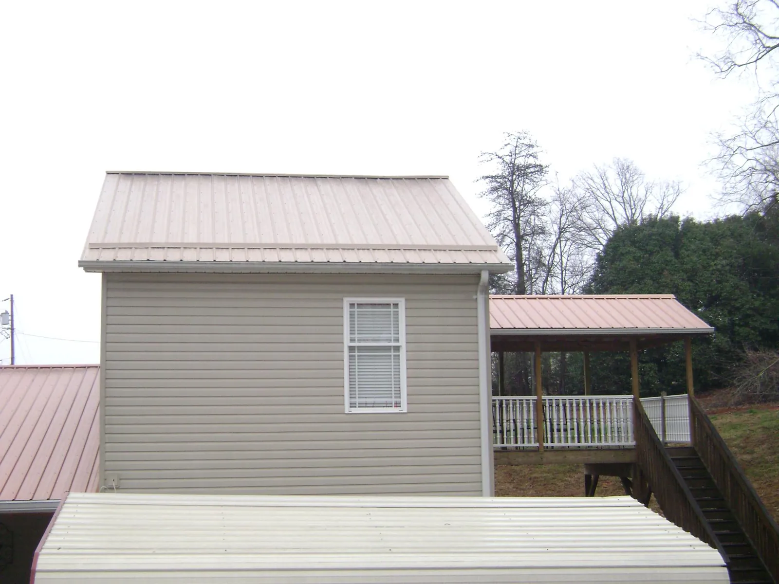 Tan metal roofs on a two story addition and attached porch, from a Roof Replacement job in Martinez