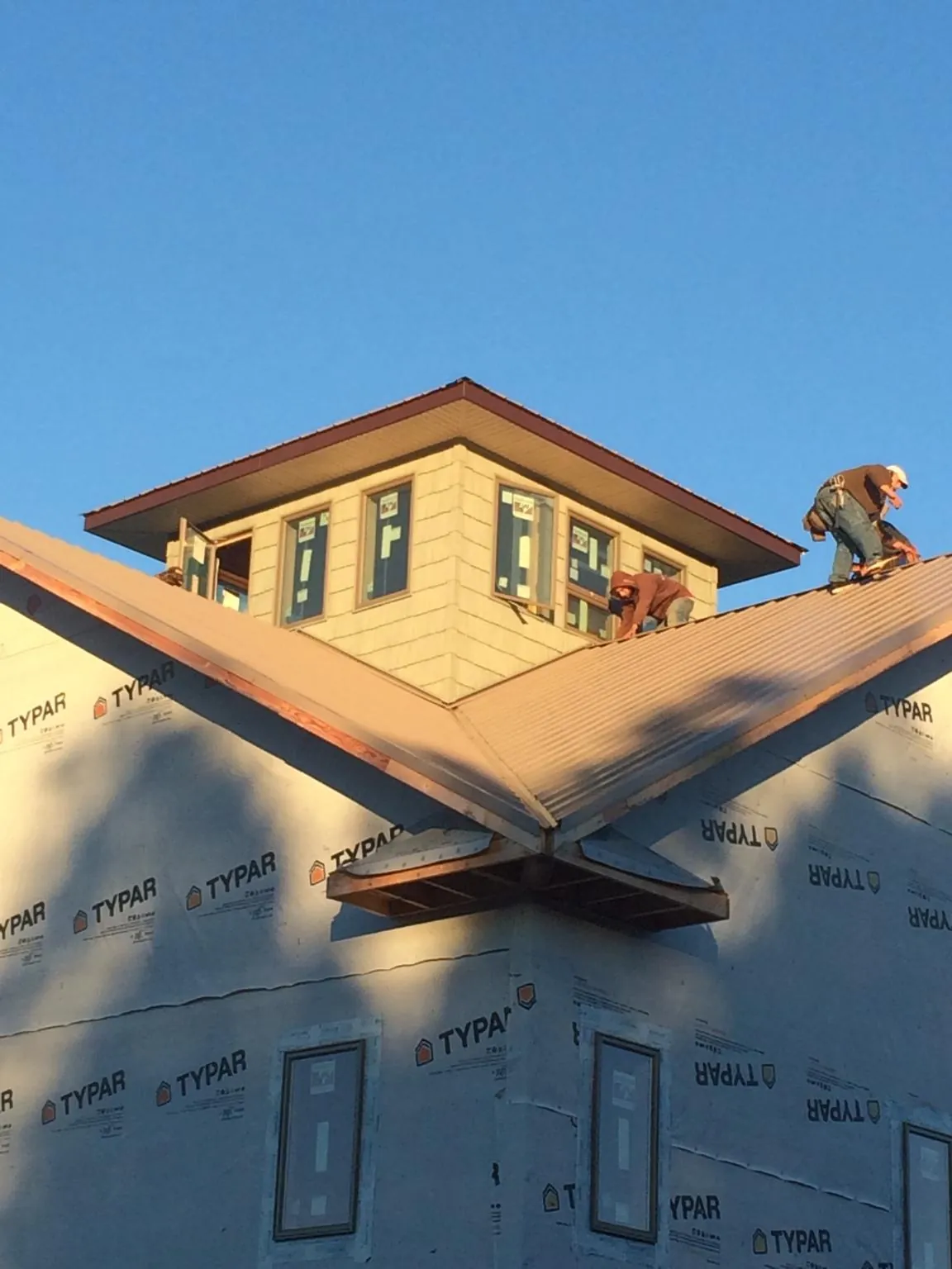 Roofers working around a rooftop cupola on a new metal roof at sunset — Roof Waterproofing in Martinez by Roofing Brothers